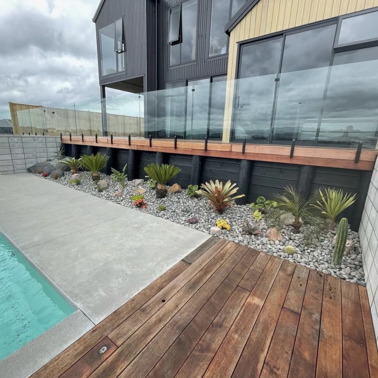 Modern house with black and beige siding and a landscaped yard